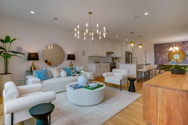 living room with sink, a chandelier, and light hardwood / wood-style flooring