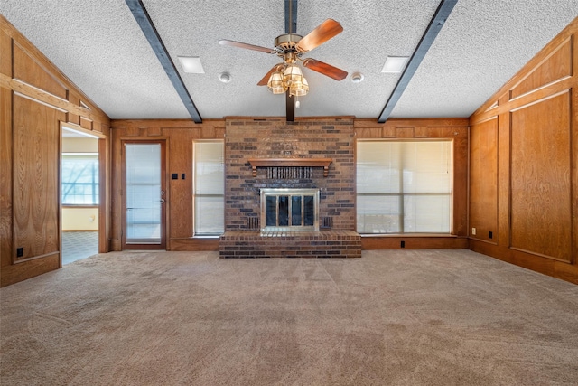 unfurnished living room with a fireplace, wooden walls, vaulted ceiling with beams, and carpet flooring