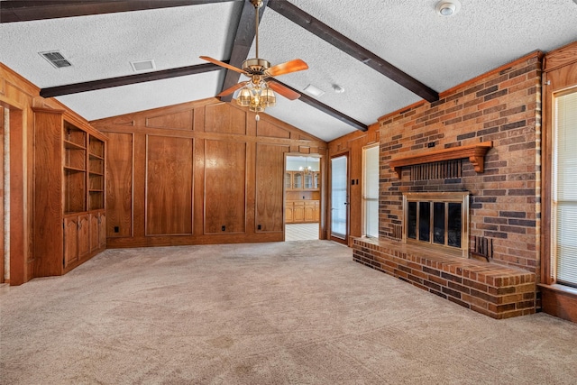 unfurnished living room with vaulted ceiling with beams, wooden walls, a fireplace, a textured ceiling, and light colored carpet