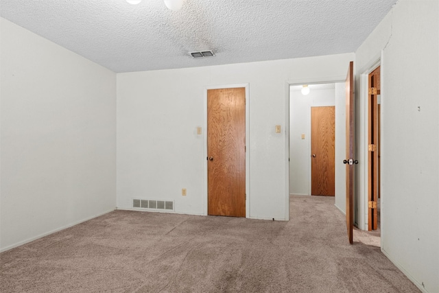 unfurnished bedroom featuring light colored carpet and a textured ceiling