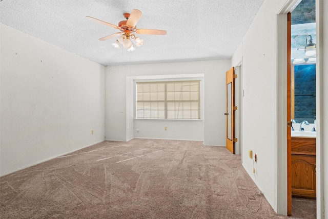 empty room with ceiling fan, sink, light carpet, and a textured ceiling