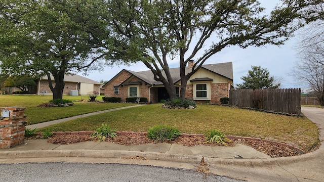 view of front of house with a front yard, brick siding, fence, and a chimney