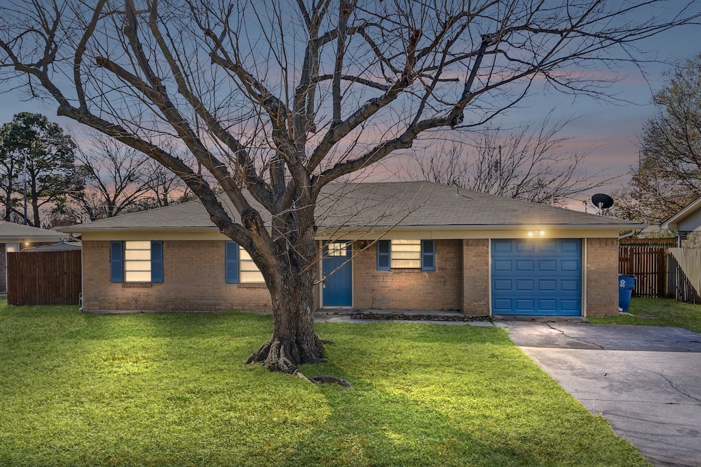 ranch-style house with a garage and a lawn