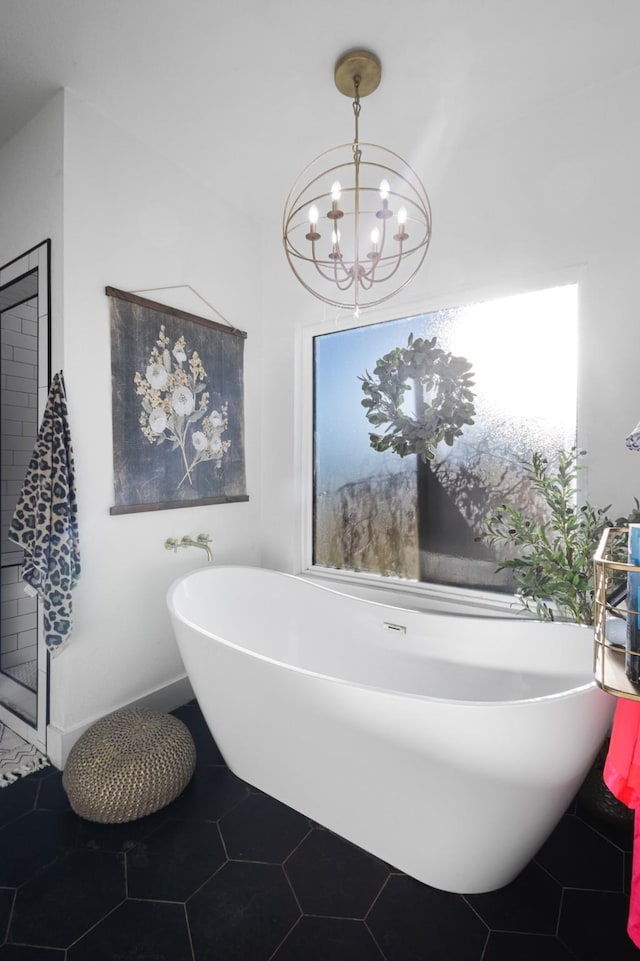 bathroom with tile patterned floors, a chandelier, and a bathing tub