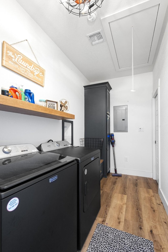 laundry room with cabinets, electric panel, washing machine and dryer, and light wood-type flooring