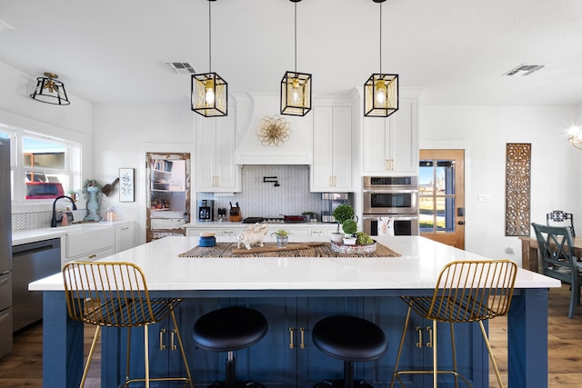 kitchen with hanging light fixtures, a kitchen breakfast bar, a kitchen island, stainless steel appliances, and white cabinets