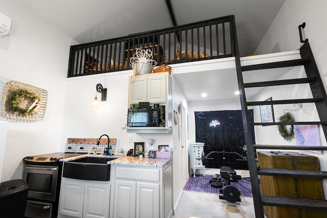 kitchen featuring stainless steel electric stove, an AC wall unit, white cabinetry, sink, and backsplash