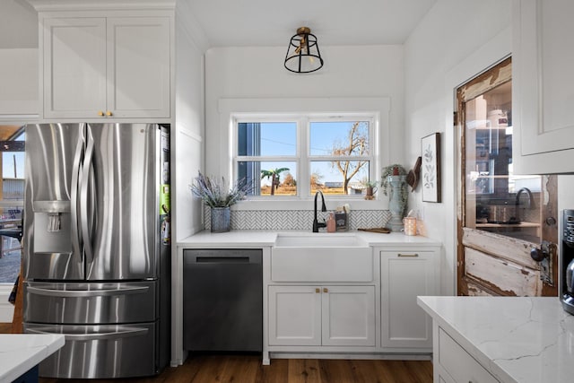 kitchen with sink, light stone counters, stainless steel fridge with ice dispenser, black dishwasher, and white cabinets