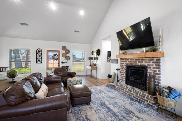 living room with wood-type flooring, high vaulted ceiling, and a brick fireplace