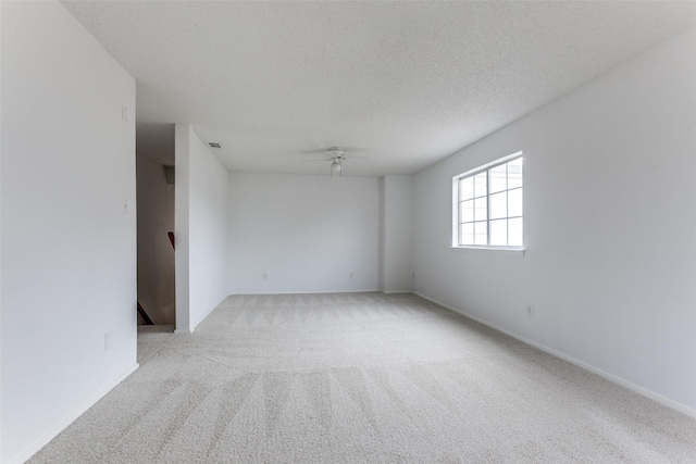 spare room featuring ceiling fan, light colored carpet, and a textured ceiling