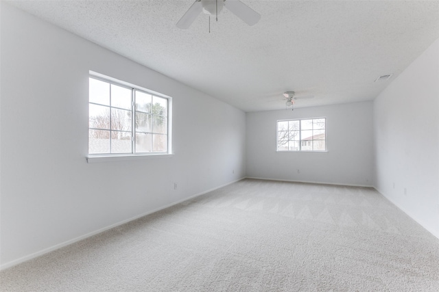 empty room featuring ceiling fan, light colored carpet, and a textured ceiling