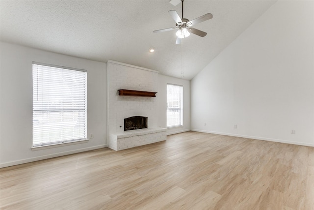 unfurnished living room with ceiling fan, a healthy amount of sunlight, a fireplace, and light hardwood / wood-style floors