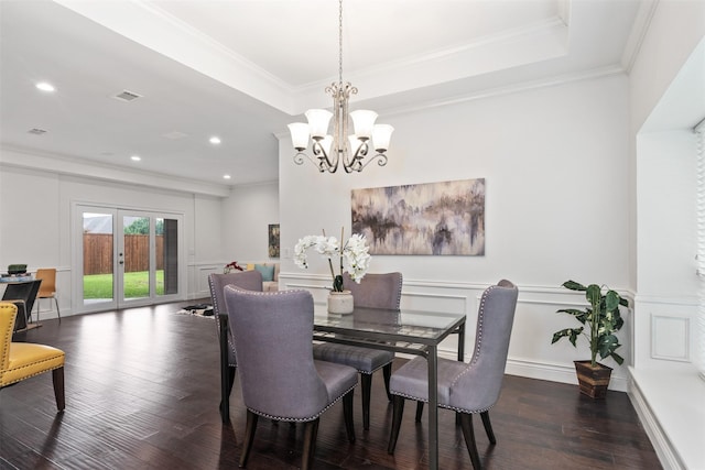 dining space with crown molding, an inviting chandelier, a tray ceiling, dark hardwood / wood-style flooring, and french doors