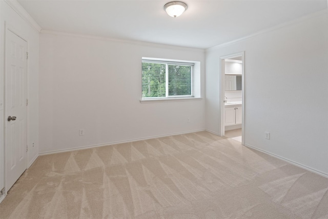 unfurnished bedroom featuring crown molding, connected bathroom, baseboards, and light carpet