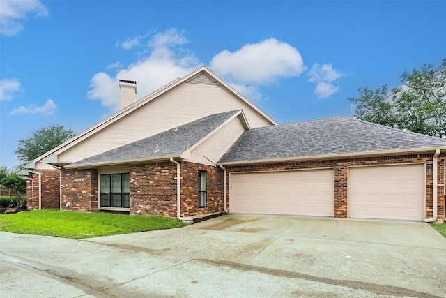 view of front of property with driveway, an attached garage, a shingled roof, a front lawn, and brick siding