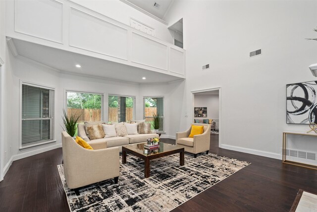 living room featuring a high ceiling, ornamental molding, and dark wood-type flooring