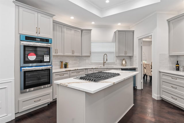 kitchen featuring dark wood-type flooring, ornamental molding, a sink, appliances with stainless steel finishes, and light stone countertops