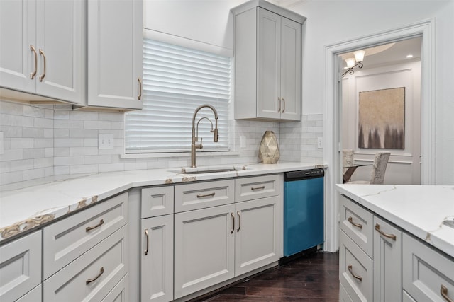 kitchen with dark wood-type flooring, a sink, backsplash, dishwashing machine, and light stone countertops