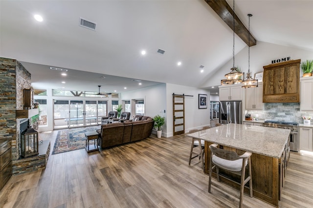 kitchen featuring stainless steel appliances, a barn door, white cabinets, and a spacious island