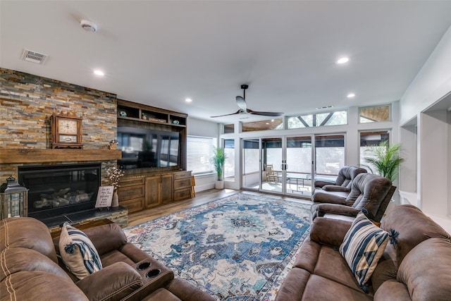 living room with hardwood / wood-style flooring, ceiling fan, a fireplace, and built in shelves