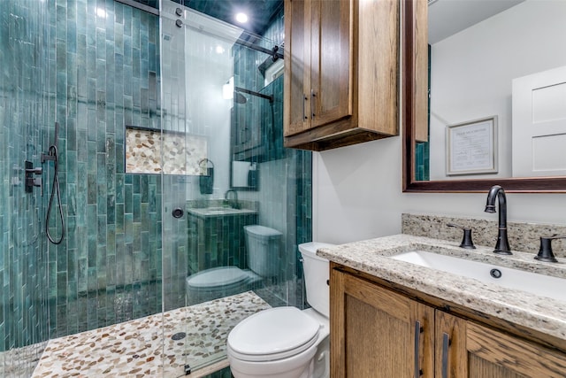 bathroom featuring vanity, a shower with shower door, and toilet