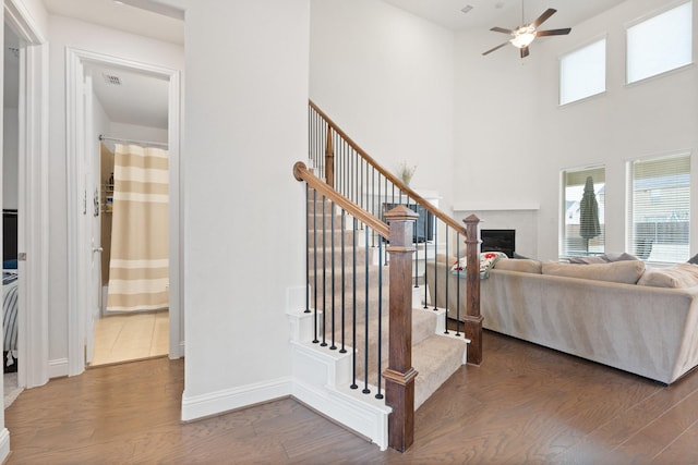 stairway featuring ceiling fan, wood-type flooring, and a towering ceiling