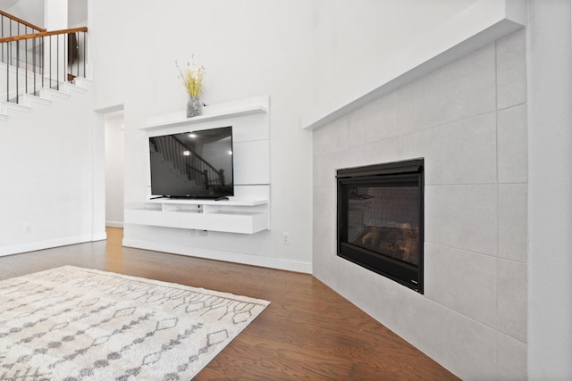 living room with a high ceiling, dark hardwood / wood-style flooring, and a fireplace