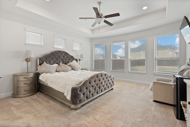 carpeted bedroom featuring a tray ceiling and ceiling fan