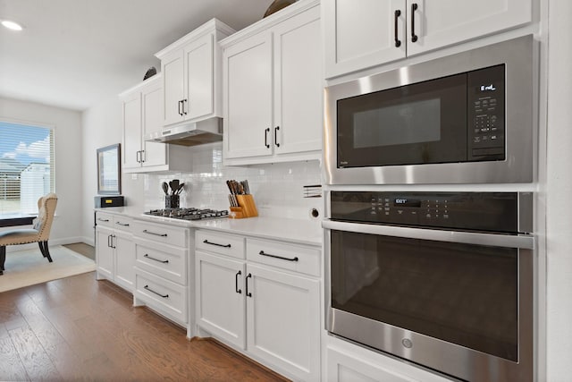 kitchen with backsplash, appliances with stainless steel finishes, dark hardwood / wood-style flooring, and white cabinets