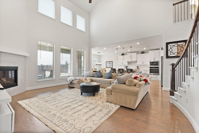 living room with hardwood / wood-style floors, a notable chandelier, and a tile fireplace