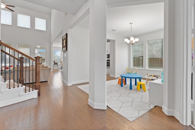 entryway with wood-type flooring and ceiling fan with notable chandelier