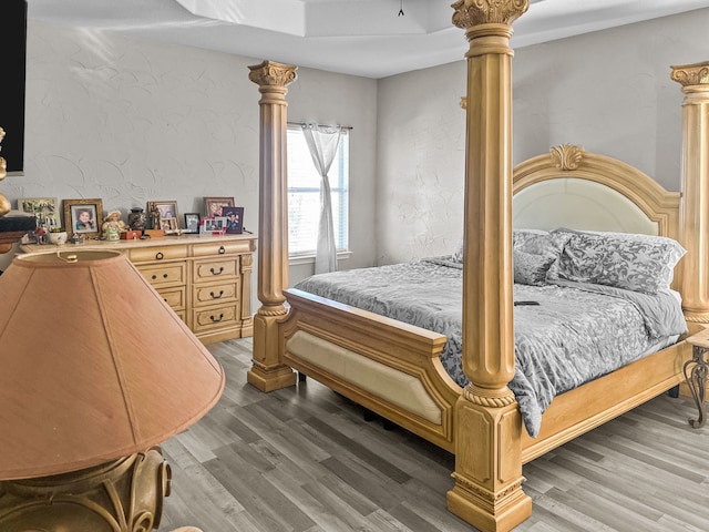 bedroom featuring decorative columns and wood-type flooring