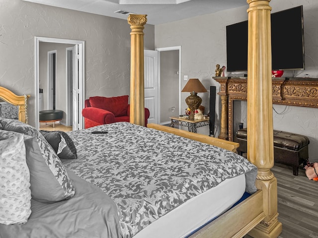 bedroom with hardwood / wood-style flooring and ornate columns