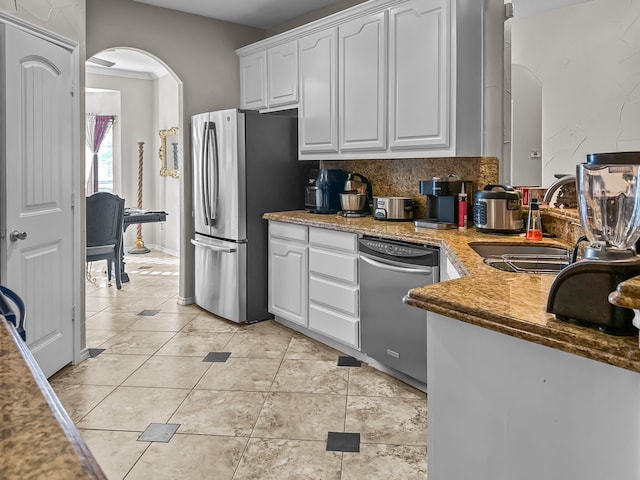 kitchen with sink, tasteful backsplash, light tile patterned floors, stainless steel appliances, and white cabinets