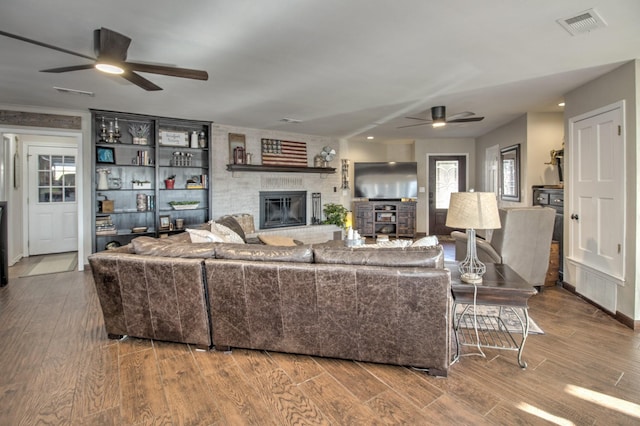 living room with ceiling fan, a fireplace, and hardwood / wood-style floors