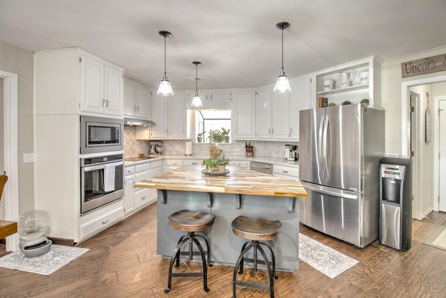 kitchen featuring white cabinetry, stainless steel appliances, a kitchen breakfast bar, a kitchen island, and wood counters