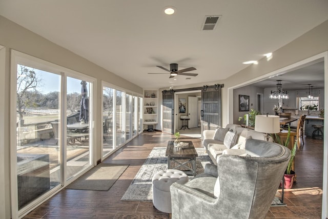 sunroom / solarium with a barn door and ceiling fan with notable chandelier