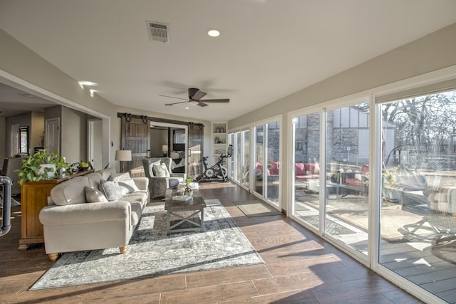 sunroom / solarium with a barn door and ceiling fan