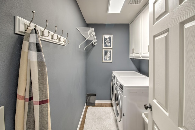 laundry area featuring cabinets, washing machine and clothes dryer, and light hardwood / wood-style floors