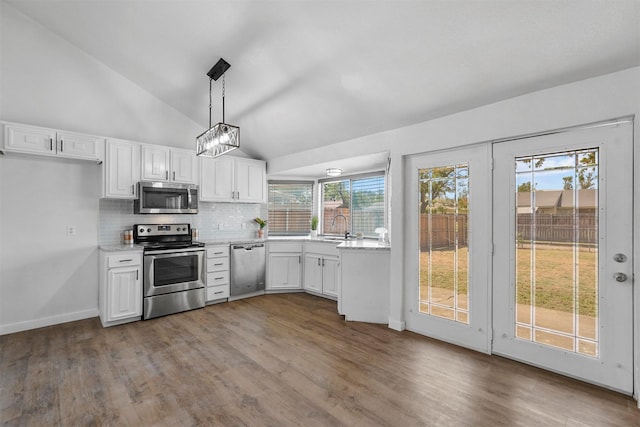 kitchen with tasteful backsplash, decorative light fixtures, hardwood / wood-style flooring, stainless steel appliances, and white cabinets