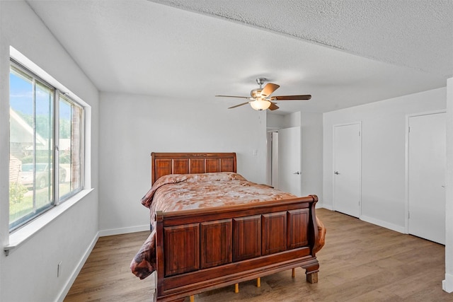 bedroom with a textured ceiling, ceiling fan, and light hardwood / wood-style floors