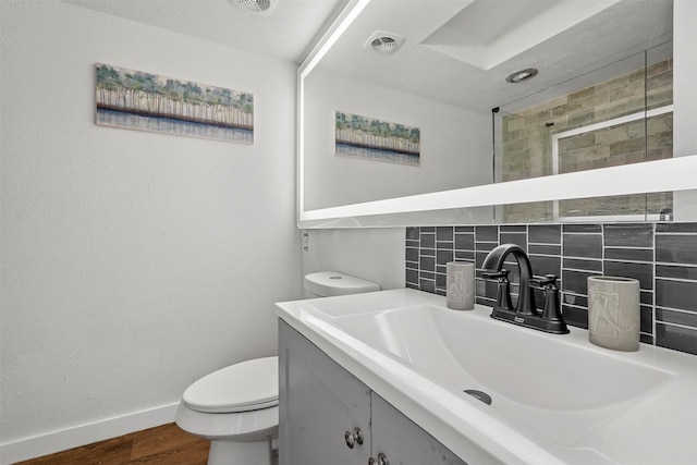 bathroom with hardwood / wood-style flooring, a shower with door, backsplash, vanity, and toilet