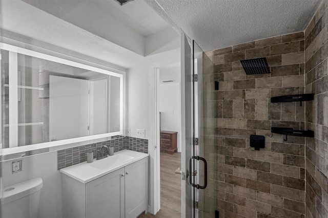 bathroom featuring toilet, an enclosed shower, tasteful backsplash, a textured ceiling, and vanity