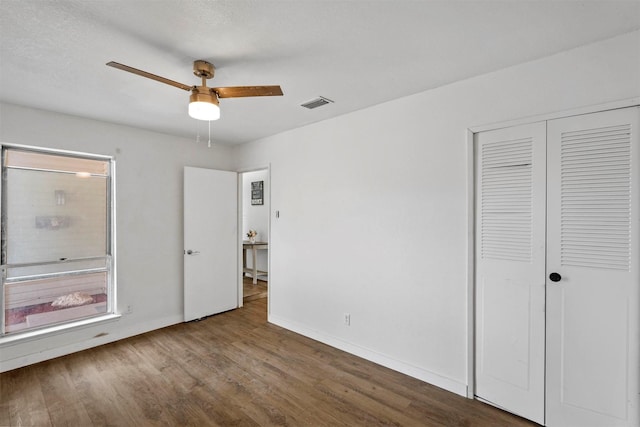 unfurnished bedroom featuring hardwood / wood-style floors, ceiling fan, and a closet