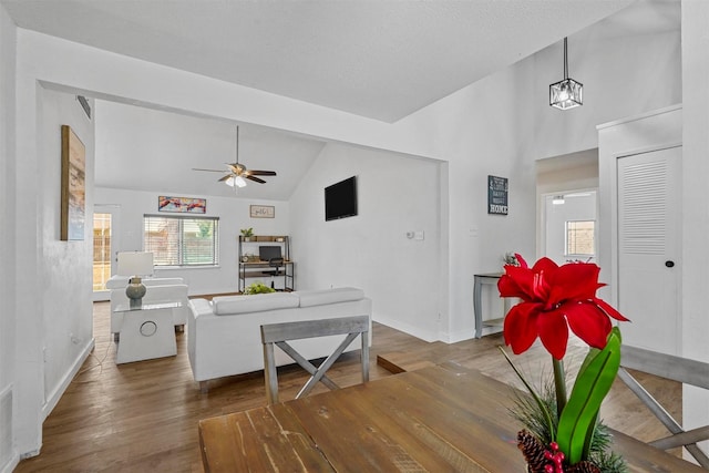 living room featuring vaulted ceiling, dark wood-type flooring, a textured ceiling, and ceiling fan