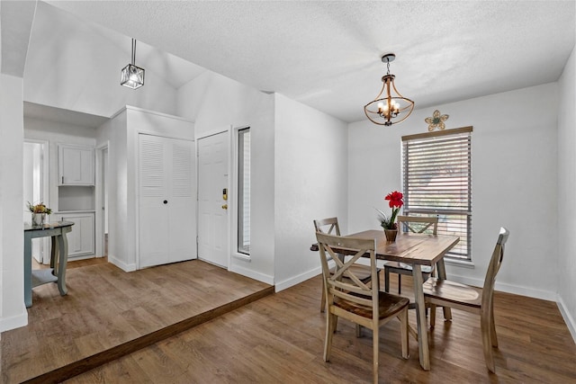 dining area featuring hardwood / wood-style floors, a textured ceiling, and a chandelier