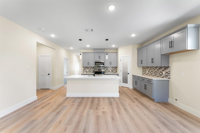 kitchen with pendant lighting, appliances with stainless steel finishes, and gray cabinetry