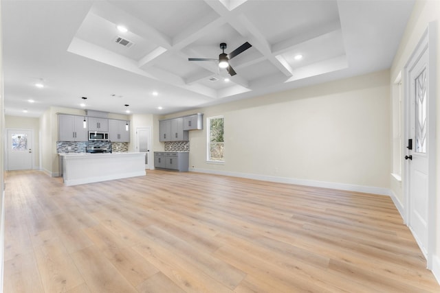 unfurnished living room featuring beamed ceiling, ceiling fan, coffered ceiling, and light hardwood / wood-style floors