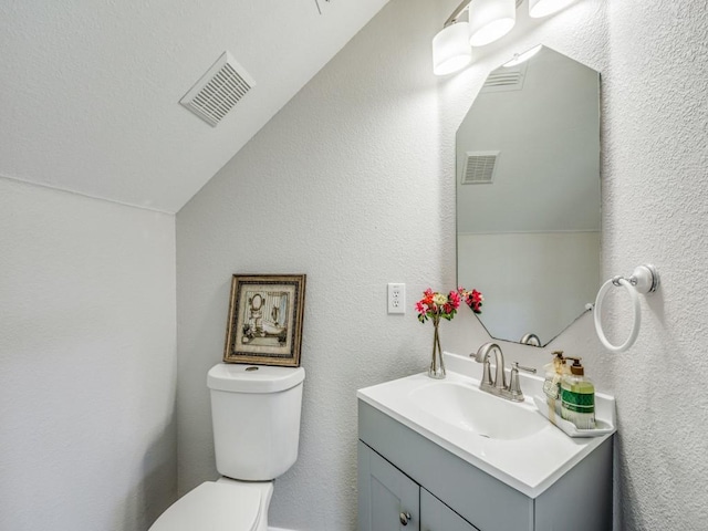 bathroom featuring vanity, vaulted ceiling, and toilet