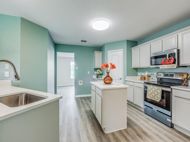 kitchen featuring white cabinetry, stainless steel appliances, sink, and a kitchen island